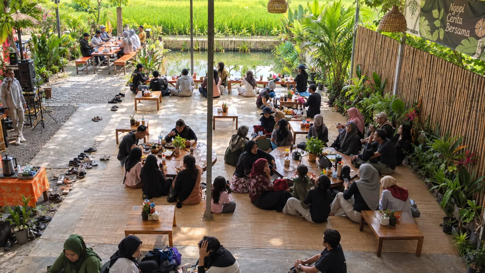 Suasana makan bersama di area lesehan dengan pemandangan sawah dan kolam